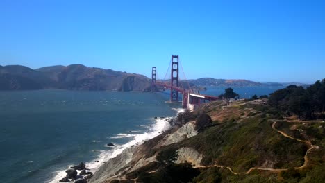 a cinematic, drone, aerial shots of the san francisco bridge featuring the landscape of the pacific ocean and its surroundings