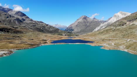 aerial flyover over lago blanco near ospizio bernina, switzerland with a view of the peaks of engadin and the tracks of the bernina express