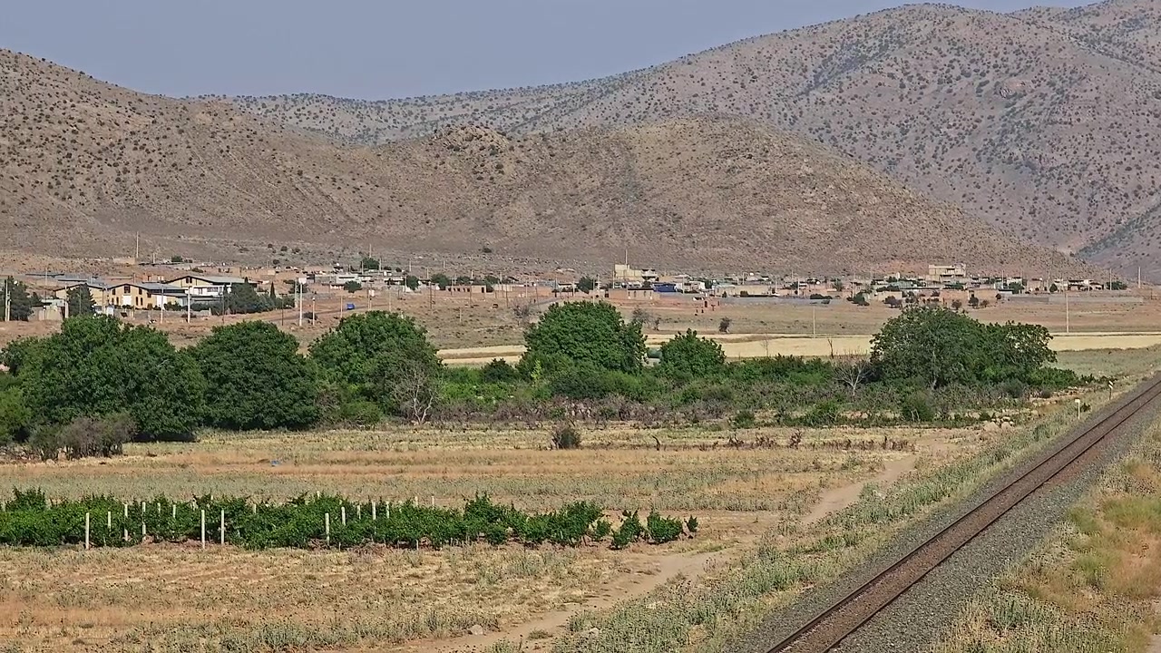 Vista panoramica di paesaggio rurale con binari ferroviari e montagne