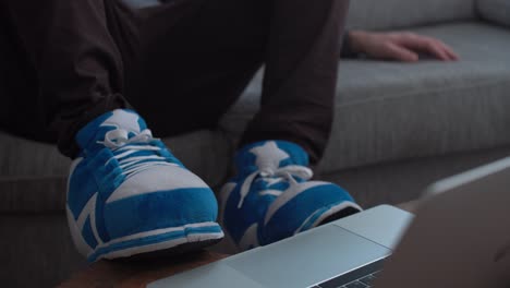 lazy guy uses slipper to work on computer while sitting on sofa