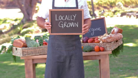 smiling farmer holding locally grown sign in slow motion