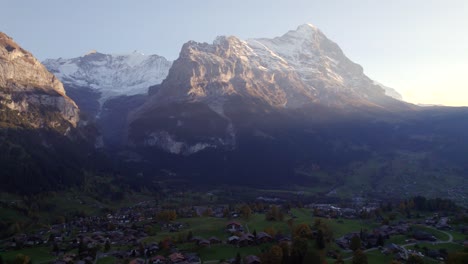 imágenes aéreas de drones empujando sobre el pueblo de grindelwald y la cara norte del eiger al atardecer en otoño