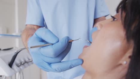 Caucasian-male-dentist-examining-teeth-of-female-patient-at-modern-dental-clinic