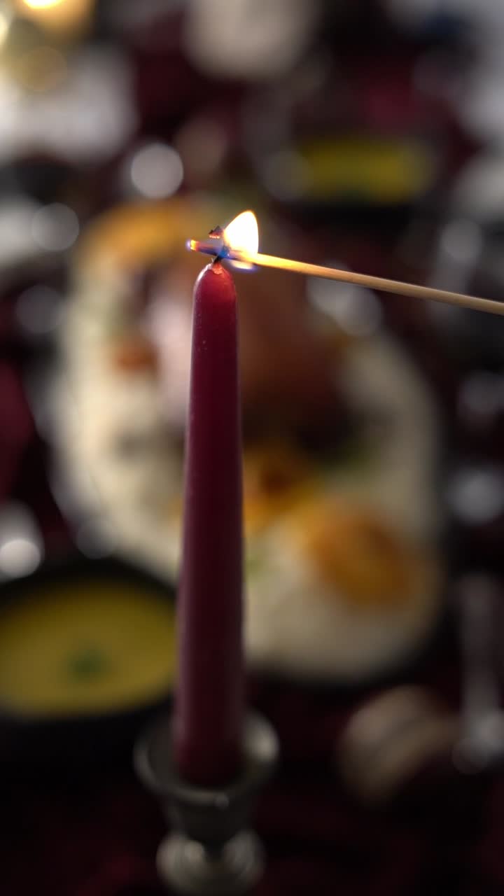 A waiter is lighting a red candle with a match during a romantic dinner, close up shot, insert shot