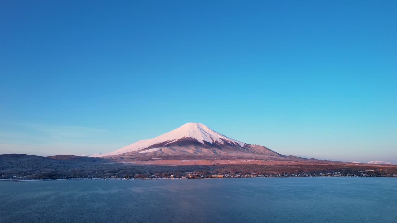 鳥の群れが朝の太陽と青い空で富士山を飛んでいます