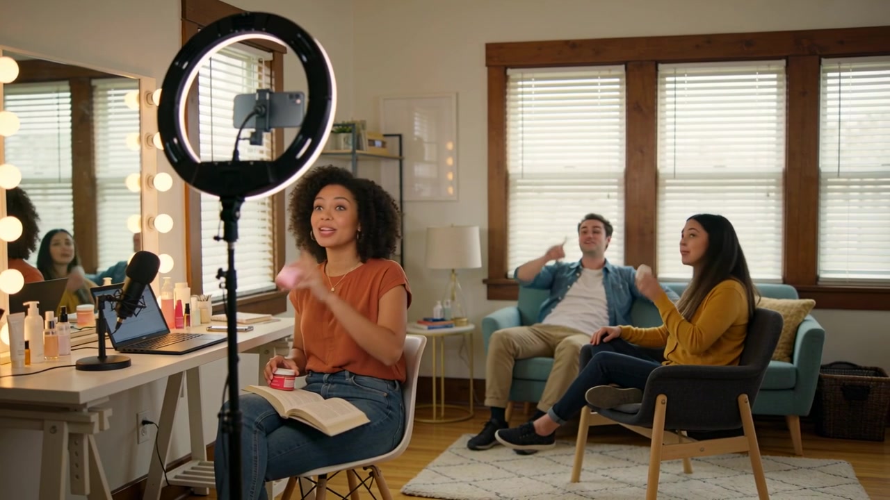 Starting ringlight recording, host in orange showing jar for demo at home vanity, friends reacting