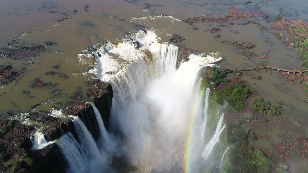 A mesmerizing view of the 'Garganta do Diabo' at Iguazu Falls, adorned with a vibrant rainbow, showcasing the natural wonder and majesty of this iconic waterfall