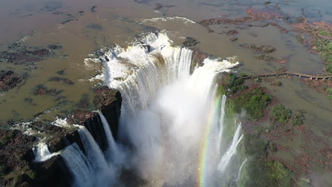 una vista hipnótica de la 'garganta do diabo' en las cataratas de iguazu, adornada con un vibrante arco iris, que muestra la maravilla natural y la majestuosidad de esta icónica cascada