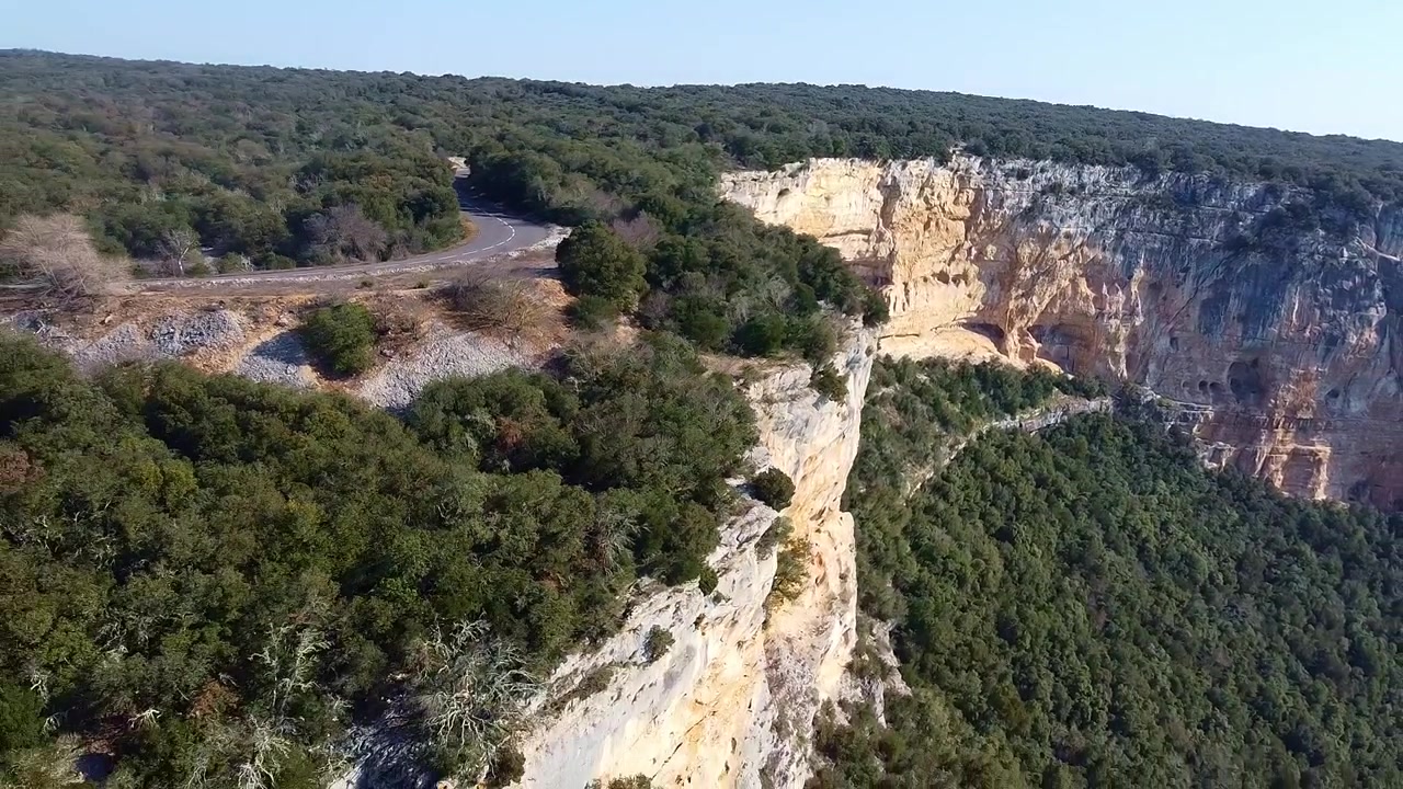 Foresta e scogliere accanto a una splendida curva della strada. Vista aerea da lontano.