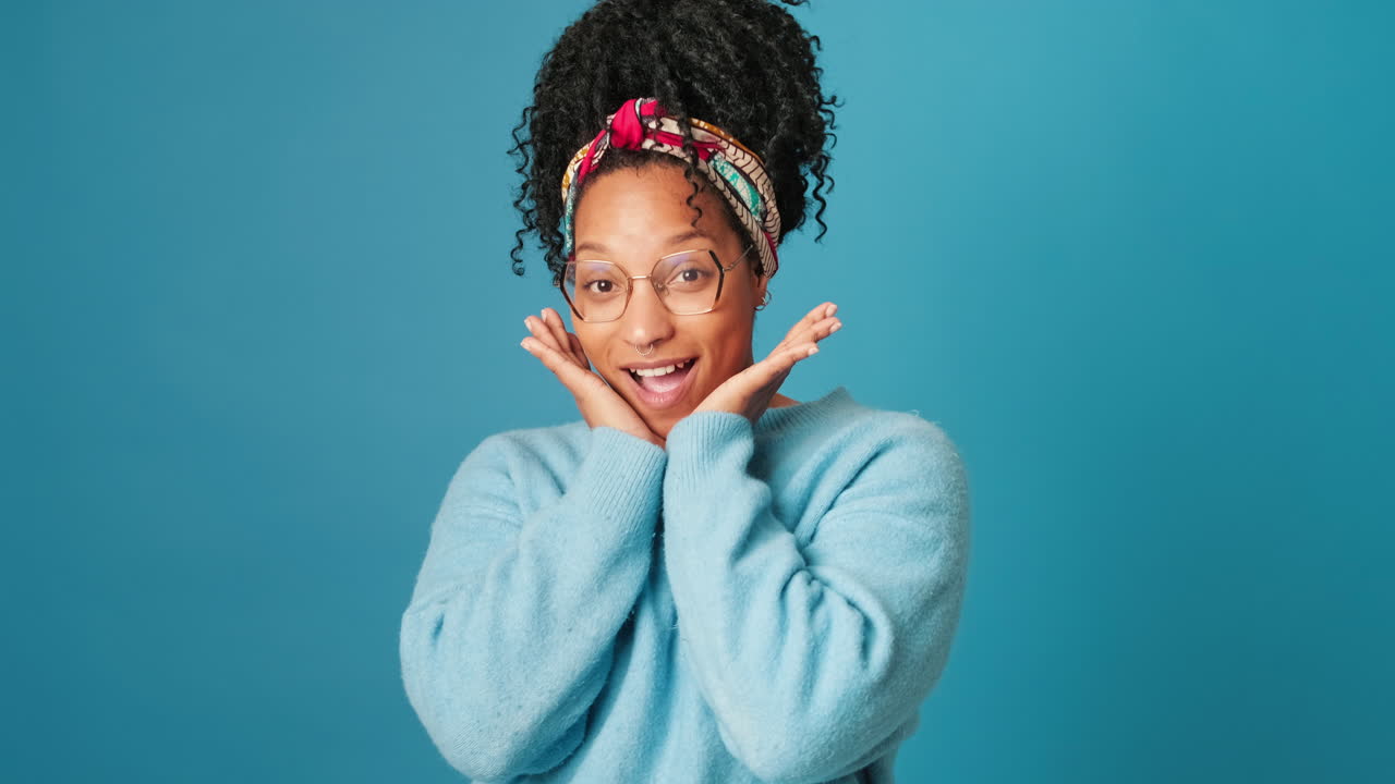 Young Woman Expressing Surprise and Delight on Blue Background