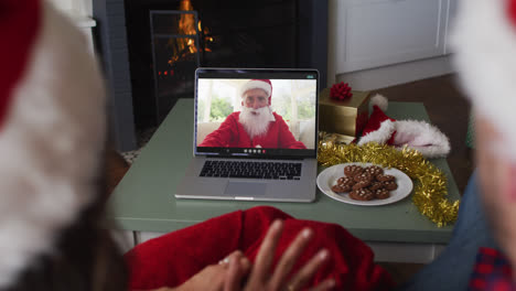 Rückansicht-Eines-Kaukasischen-Paares-Mit-Weihnachtsmützen,-Das-Während-Der-Weihnachtszeit-Einen-Videoanruf-Auf-Dem-Laptop-Führt