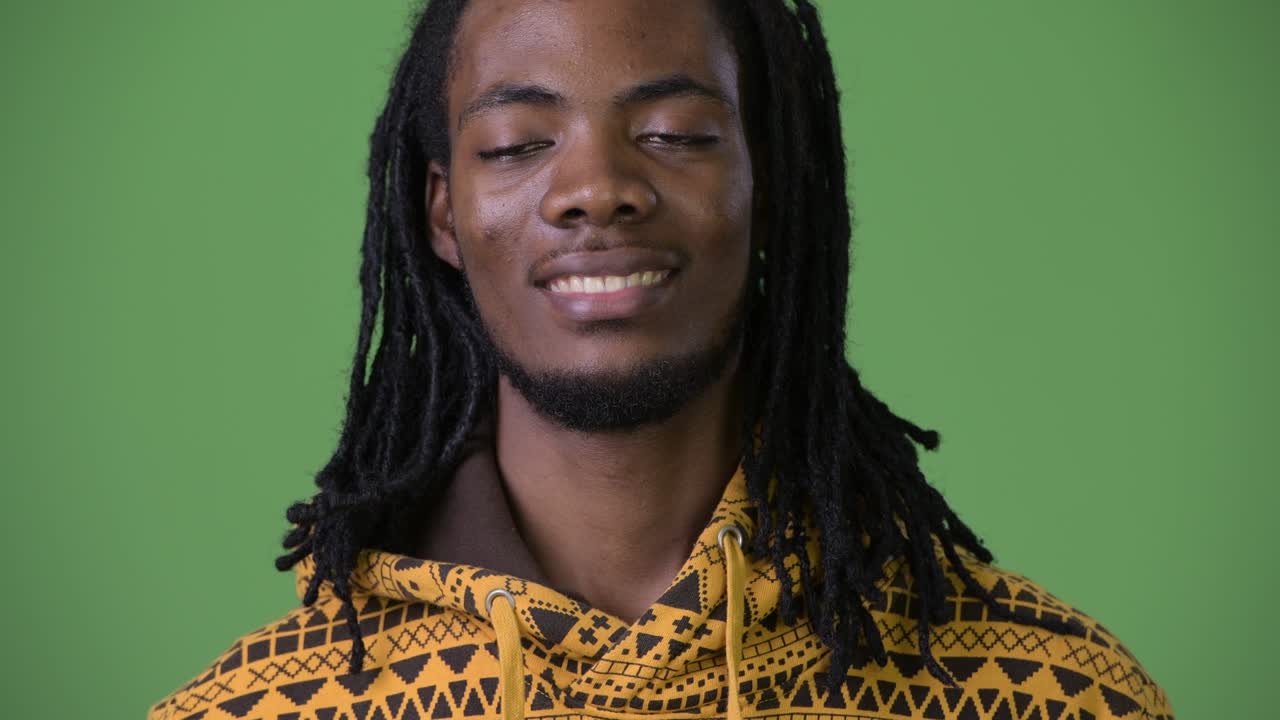 joven hombre africano guapo con dreadlocks contra un fondo verde