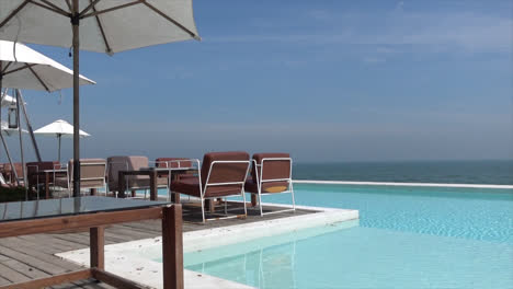 chair and umbrella with swimming pool and sea beach background