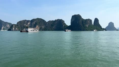 Sonniger-Tag-In-Der-Halong-bucht-Mit-Junk-booten,-Die-Felsformationen-Umgeben