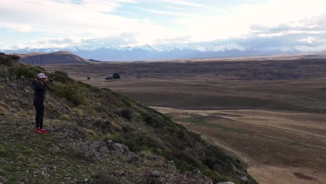 una joven rubia con una cámara tomando fotos de paisajes de nueva zelanda