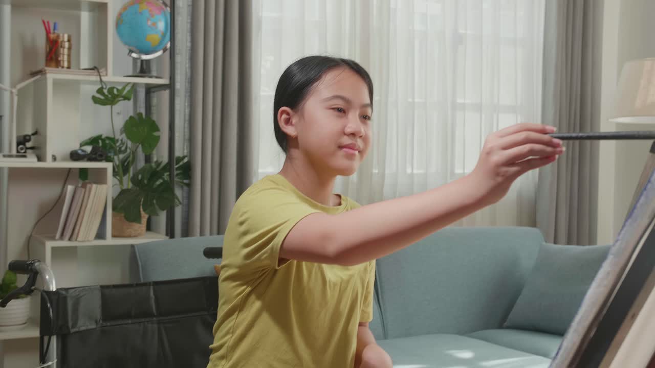 Asian Artist Girl In Wheelchair Holding Paintbrush Mixed Colour And Painting On The Canvas