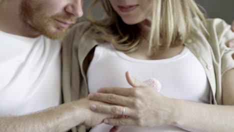 smiling future parents embracing and playing with cute booties