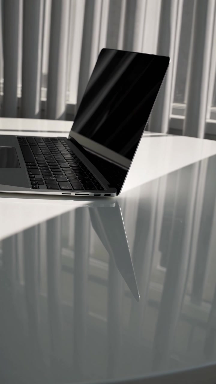 Modern Laptop Sitting on a Reflective White Desk