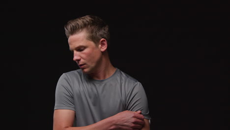 Portrait-Of-Serious-Male-Athlete-Wearing-Fitness-Clothing-Training-Warming-Up-And-Preparing-Psychologically-For-Sports-Event-Against-Black-Studio-Background