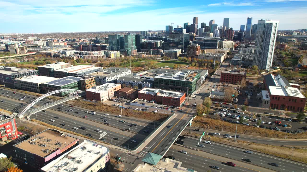 Drone aereo che inverte la rotta per rivelare auto che guidano su un'autostrada interstatale trafficata e lo skyline del centro di Denver, Colorado, USA in una luminosa giornata autunnale