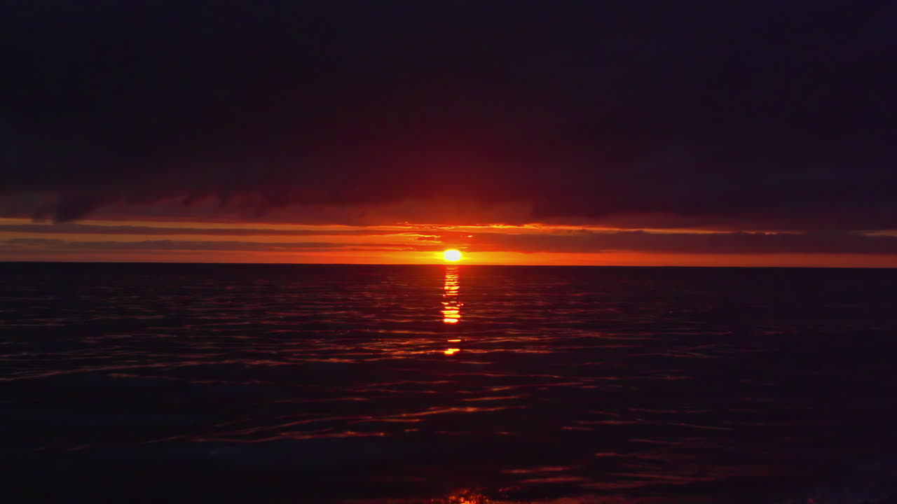 smukke billeder af havet om natten med en orange horisont og den nedgående sol lige over vandet