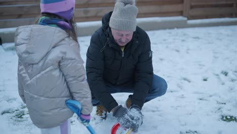 grandfather and granddaughter having fun in the snow