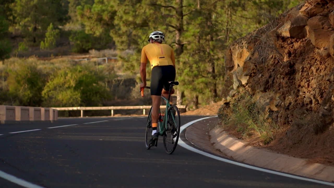 Biking on a mountain serpentine, the athlete takes in the island's stunning scenery in slow motion, showcasing the commitment to a healthy lifestyle