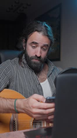musician playing acoustic guitar and taking a selfie in a home studio