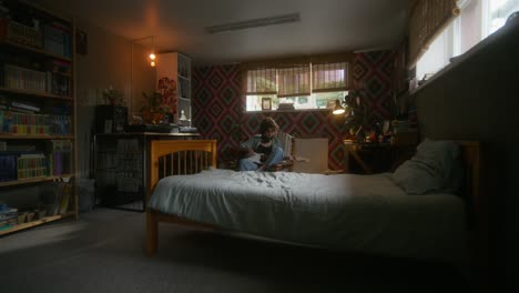 a woman playing guitar in a cozy bedroom