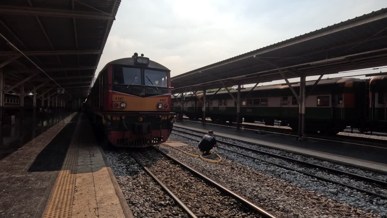 Un locomotore diesel si avvicina lentamente al binario coperto di una stazione ferroviaria urbana in una giornata di luce fioca