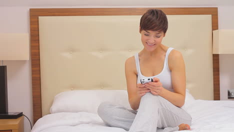 mujer enviando mensajes de texto en su teléfono inteligente en su cama