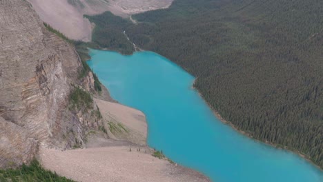 aerial lowering over emerald lake moraine between mountains and pine tree forest at banff national park, alberta, canada