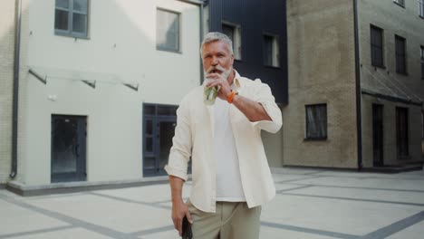 older man with drink outdoors