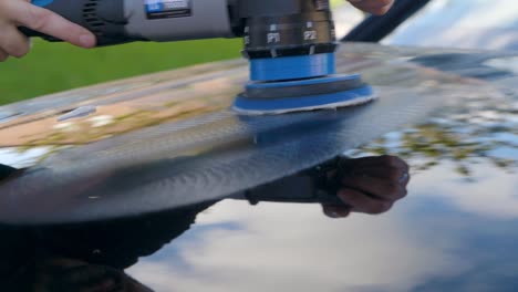 polishing a black car bonnet hood with a machine polisher