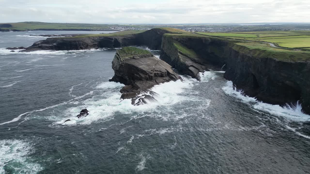 vista del acantilado de los acantilados de kilkee en irlanda con olas chocando contra las rocas, cielos nublados por encima