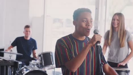 students at performing arts school playing in band at rehearsal