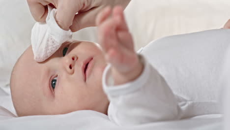 mother wipes her baby face with a handkerchief