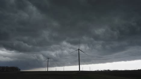wind turbines stand resilient beneath turbulent, storm-filled skies - wide shot