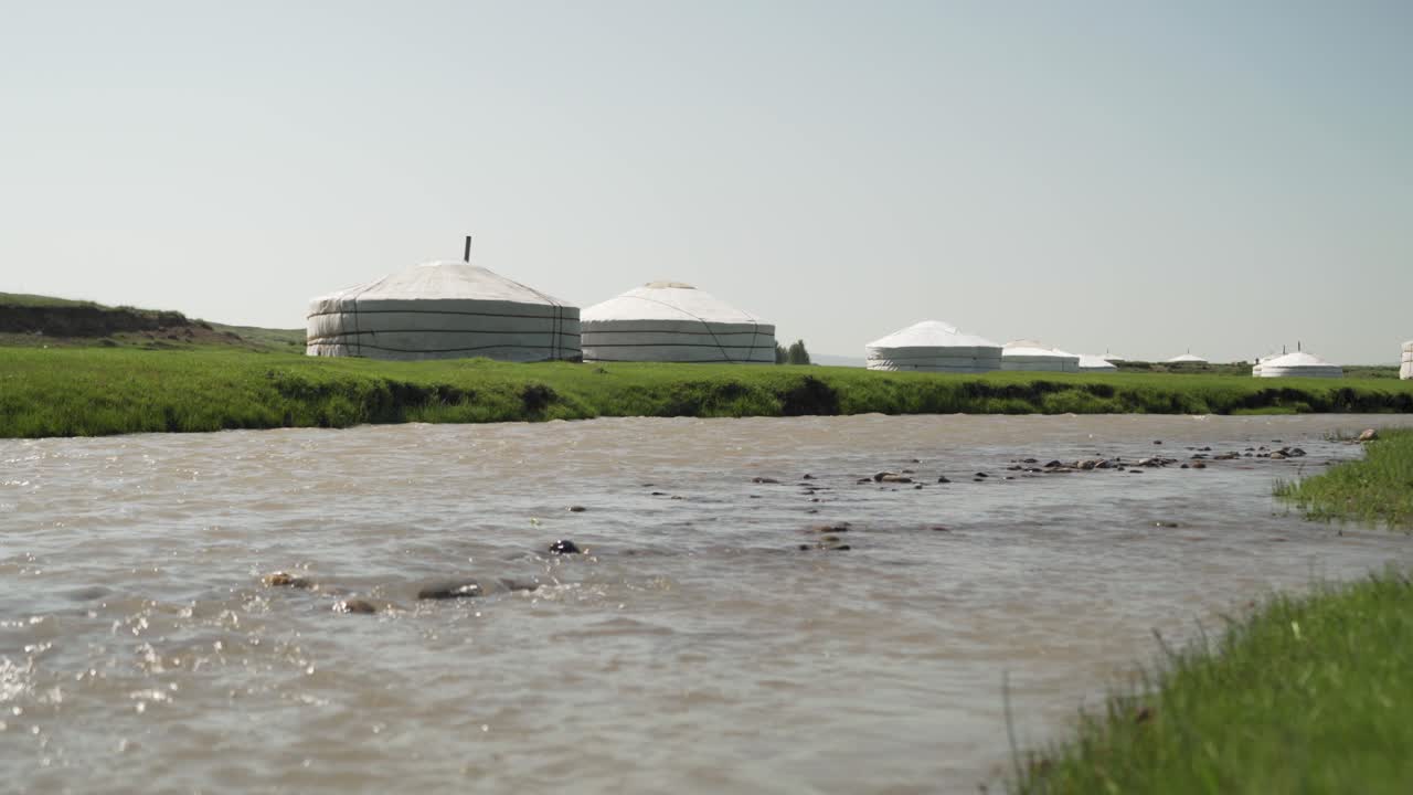 Pysäytyskuva, puro kuplii rauhallisesti paimentolaiskylän vieressä, Mongolia