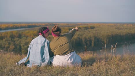 una pareja de lesbianas descansa en una colina en un río tranquilo en una noche de otoño.