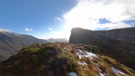 vuelo fpv sobre las montañas sunnmøre cubiertas de hierba en noruega durante un día soleado con cielo azul
