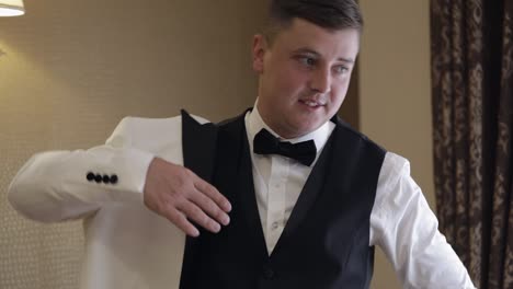 handsome stylish groom man wearing white jacket at home in living room, slow motion indoors portrait