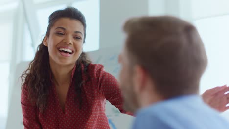 Joyful-afro-woman-praising-colleague-in-modern-office