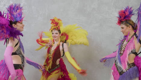 three cabaret girls dancing with colorful outfits