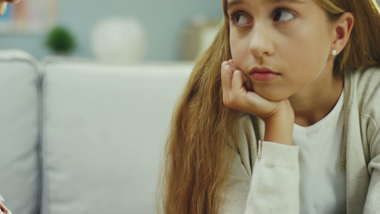 집에서 소파에 앉아있는 금발의 슬픈 십대 소녀와 그녀의 할머니가 그녀를 위로하려고하는 클로즈업. 초상화. 실내.