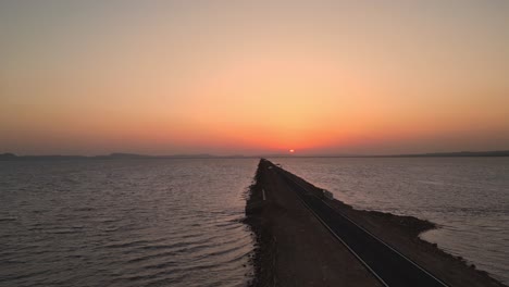 a mesmerizing view of the road to heaven in kutch, gujarat, stretching between the sea under a stunning sunset, creating a serene scene beneath a clear sky