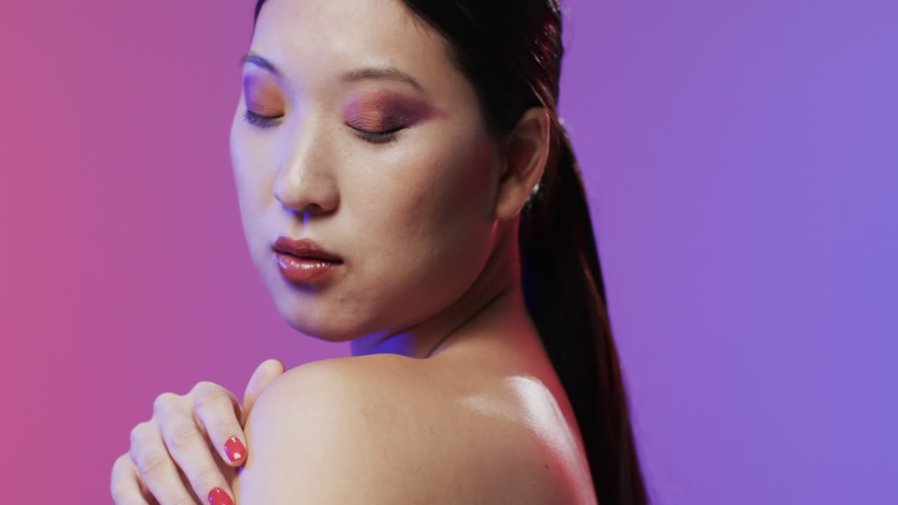 Asian woman with black hair and make up with eyes closed, copy space, slow motion