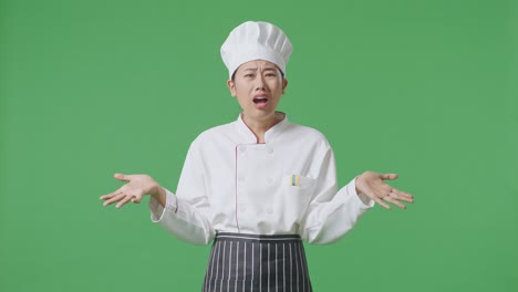 wondering asian woman chef saying why and standing doubtfully in the green screen background studio