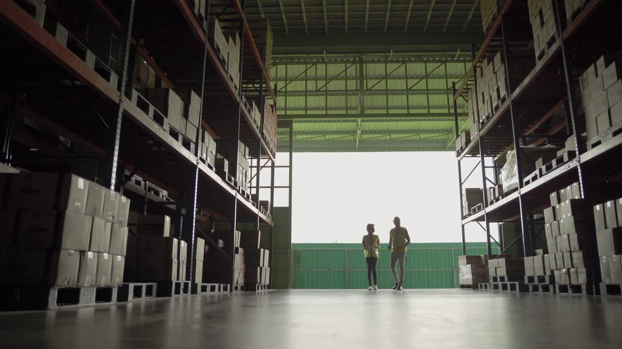 African American male and female workers walk and talking into a warehouse. Silhouette Tone
