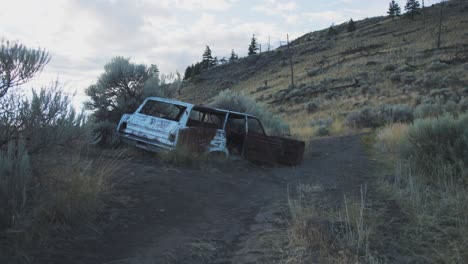 rusty abandoned car at the side of a hike trail